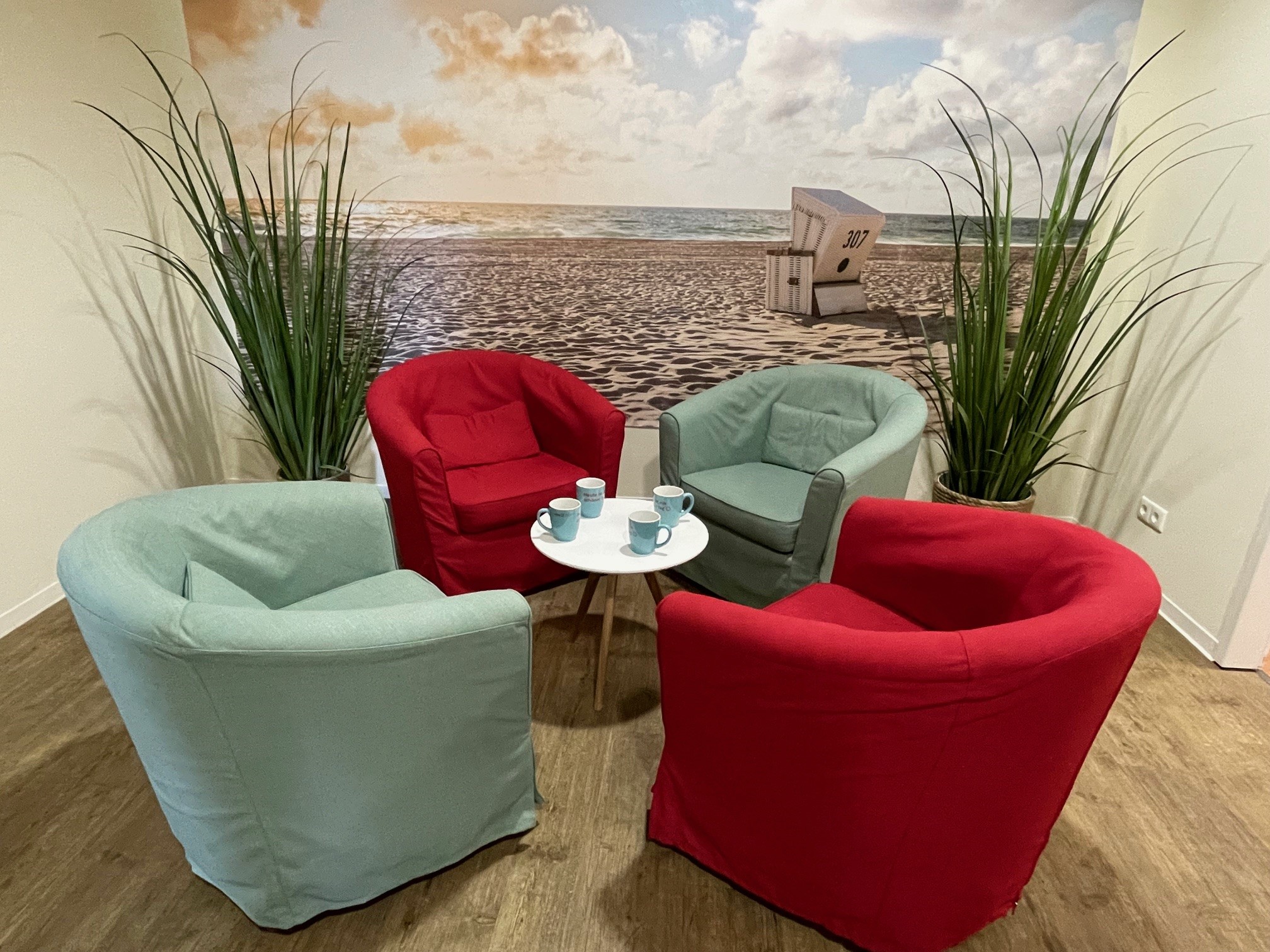 vhs Forum Sitzgruppe mit 4 Sessel, einem kleinem Tisch vor einer Nordseestrand Tapete