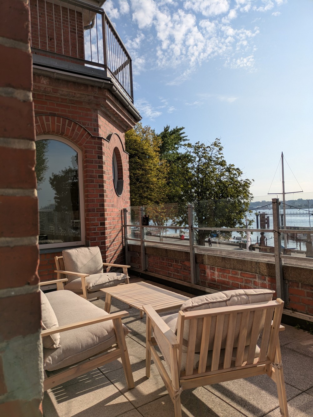 Gemütliche Lounge-Möbel und im Hintergrund die Kieler Förde und blauer Himmel.