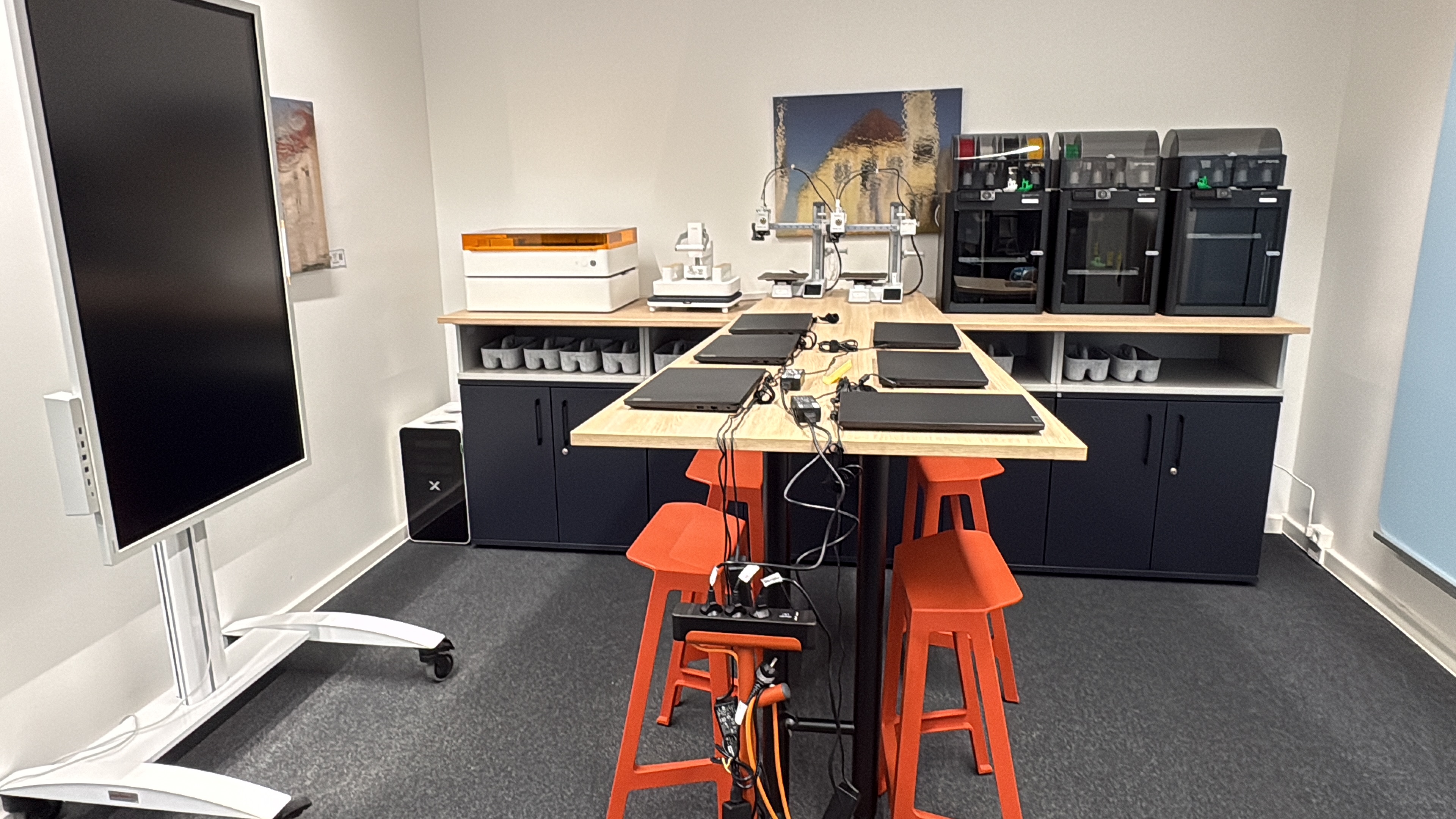Hier die Einrichtung des Makerspace in der vhs Heide: Werkbank mit vier Hockern uns 3D-Druckern