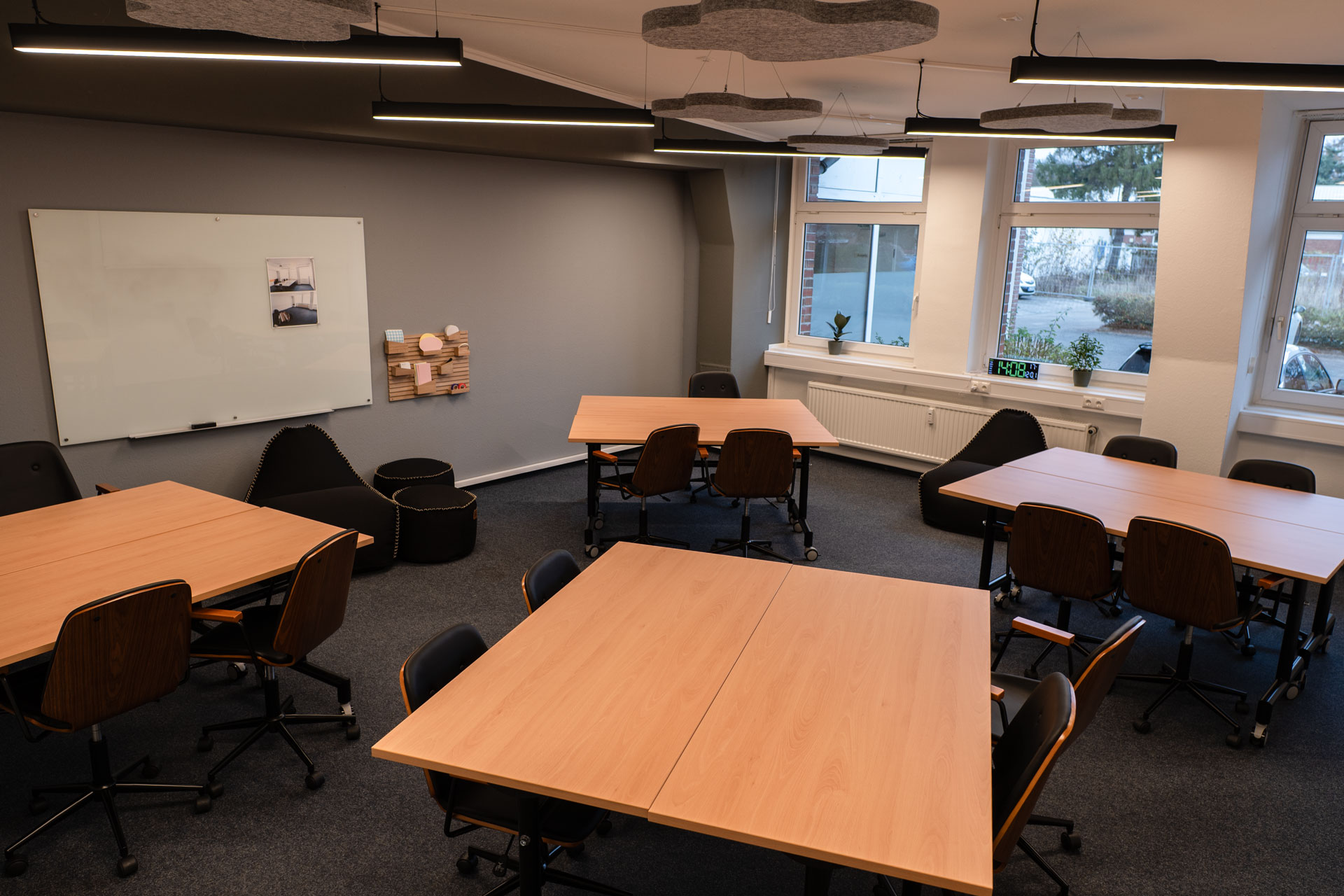 Raum mit Gruppentischen, Whiteboard und Sitzsäcken