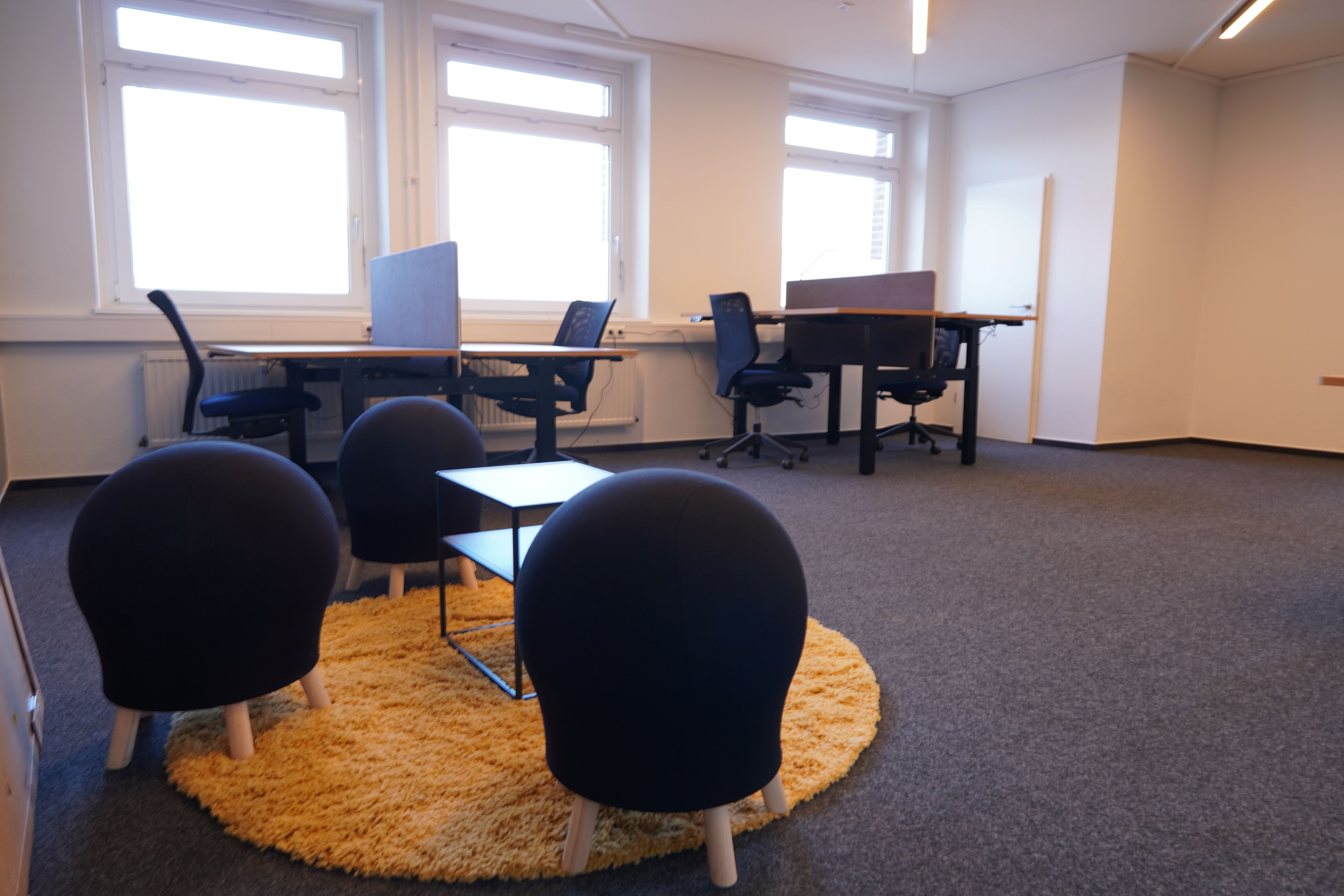 Büroraum mit höhenverstellbaren Schreibtischen und Sitzecke